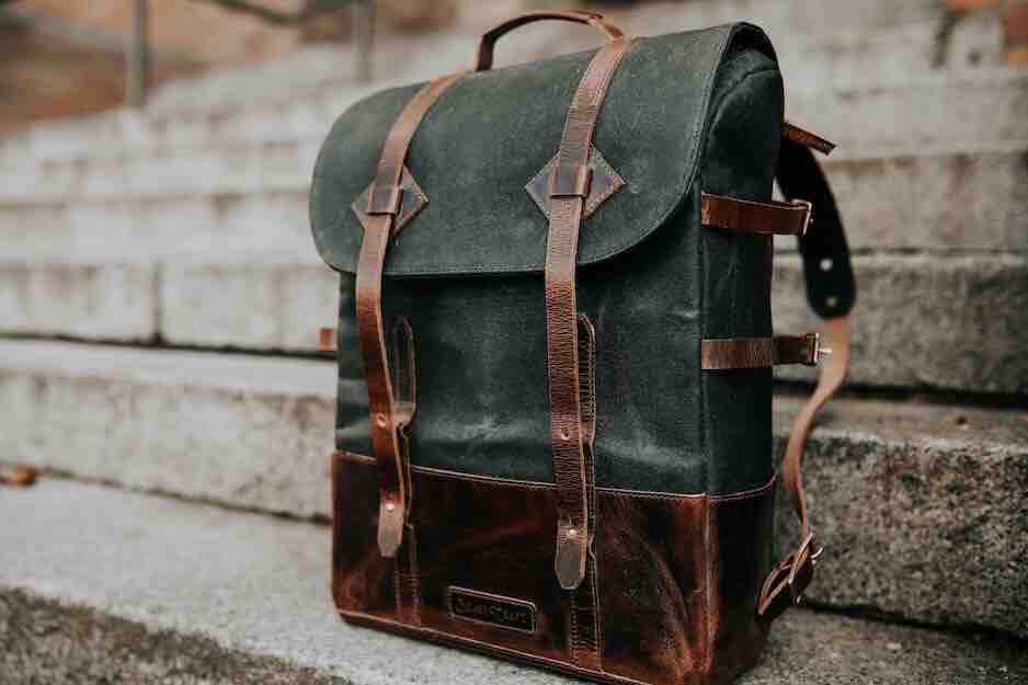 Black backpack with brown leather straps sitting on concrete stairs
