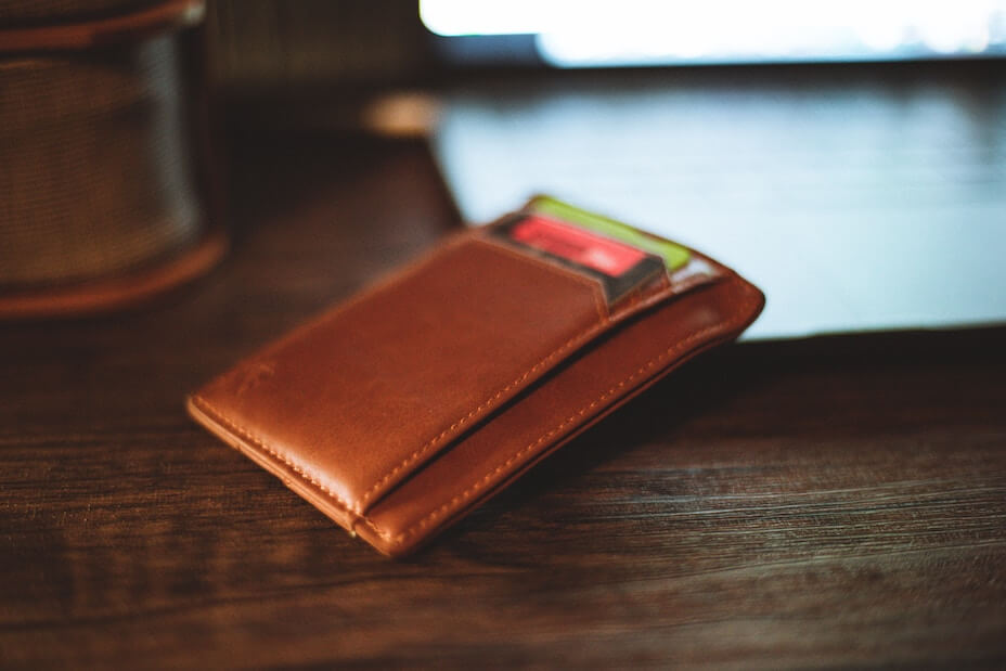 Small brown leather wallet with credit cards sitting on a wood table