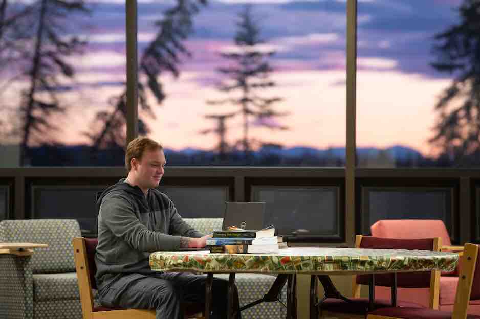 Student studying at a table with the sunrising in the background