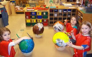 three female kids with globes in classroom