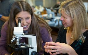 female teacher and female student looking through microscope