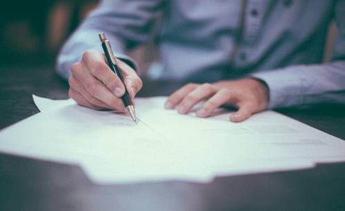 Person in button down shirt completing application with pen